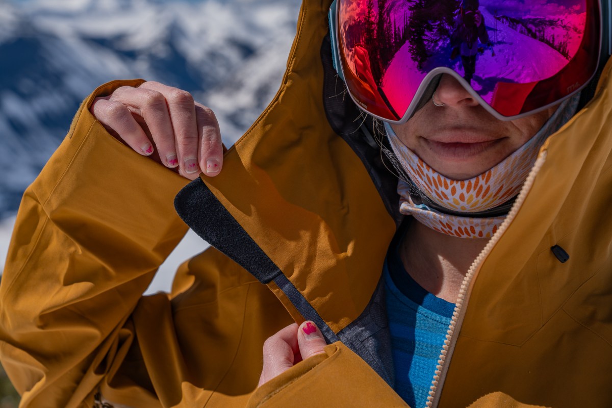 A woman skiing through deep powder wearing the light blue Arc’teryx Sentinel technical jacket.