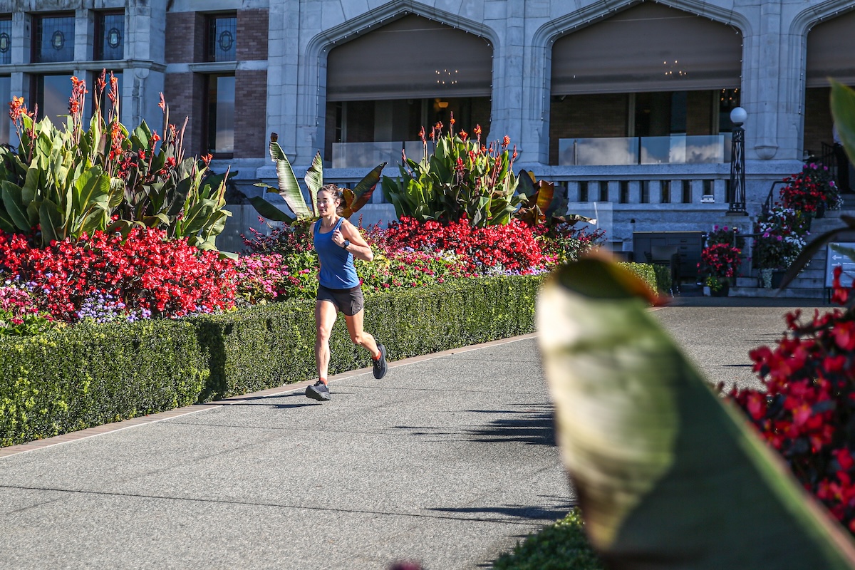A woman running on a paved city street in Hoka Bondi shoes.
