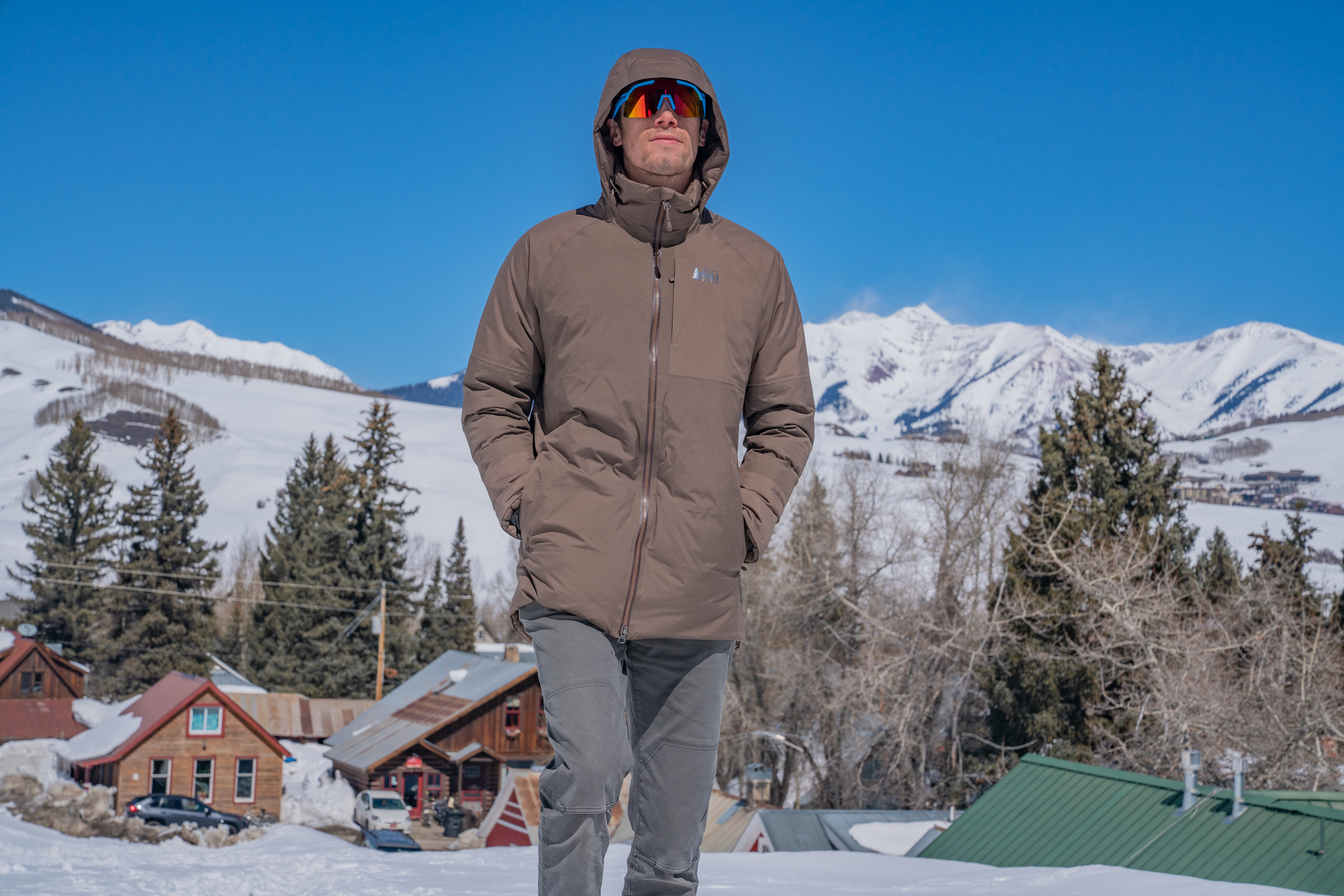 A man wearing a green REI Stormhenge Parka on a snowy street in Crested Butte.