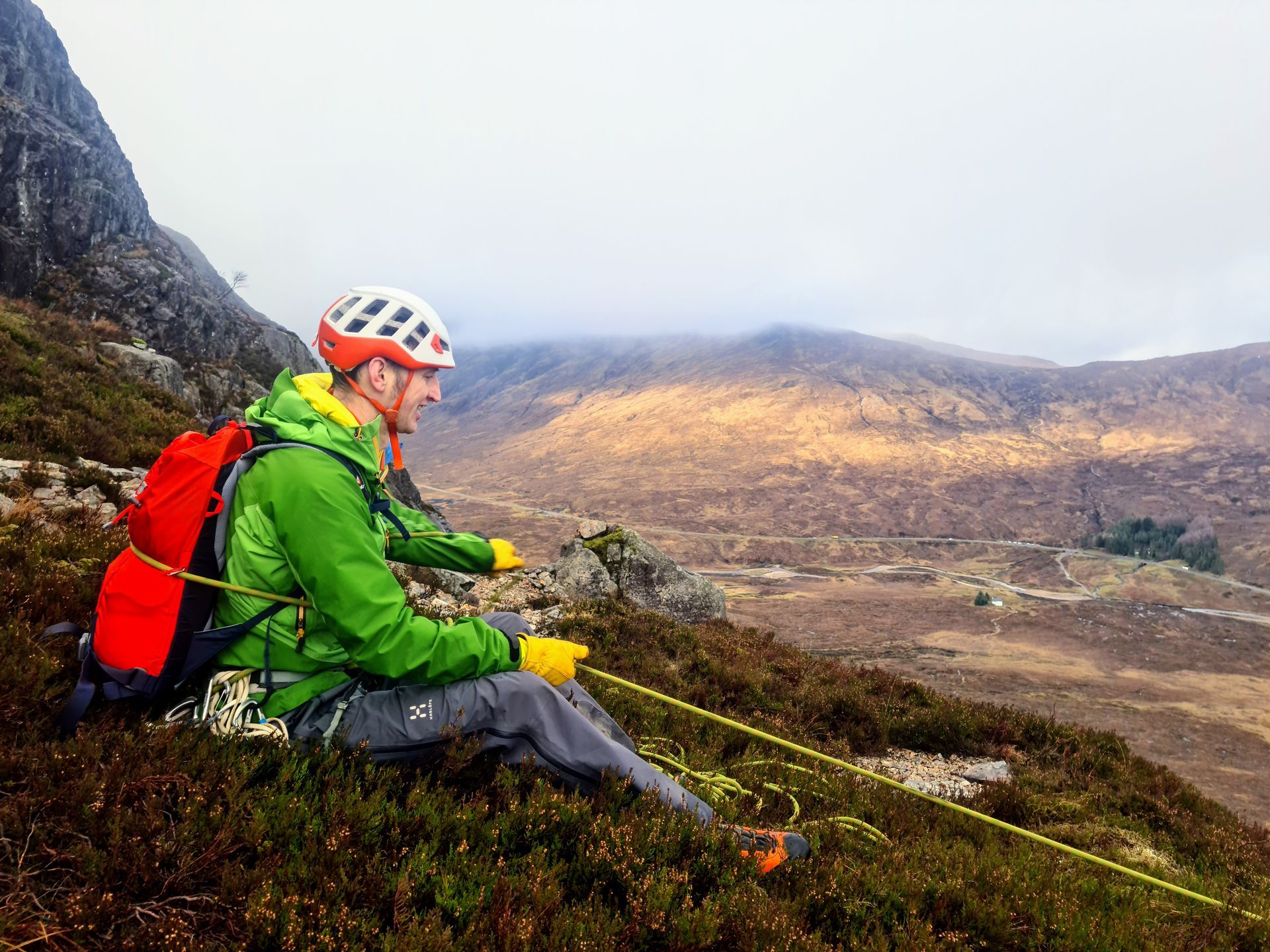 A climber demonstrating how to use a body belay to secure a partner on a steep slope.