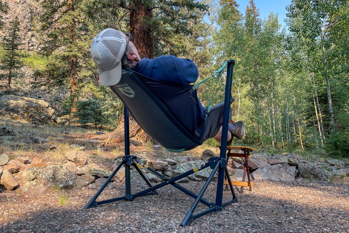 A camper reclining in a NEMO Stargaze chair at an outdoor site.