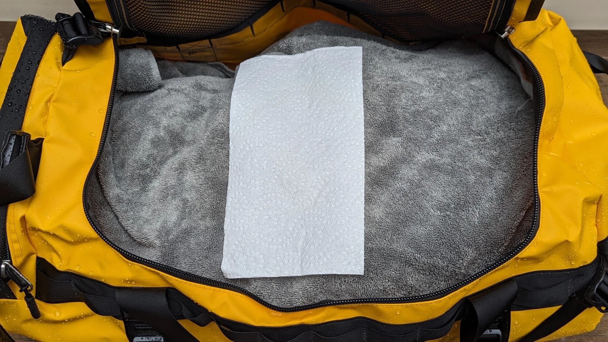 A water-resistance test where a duffel bag is being sprayed with a high-pressure hose.