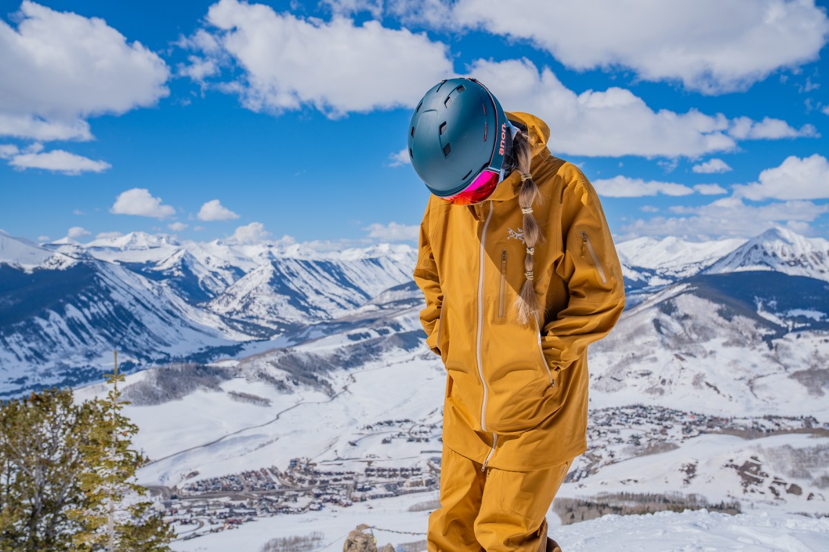 A group of female skiers in technical gear gathered in a snowy mountain environment.