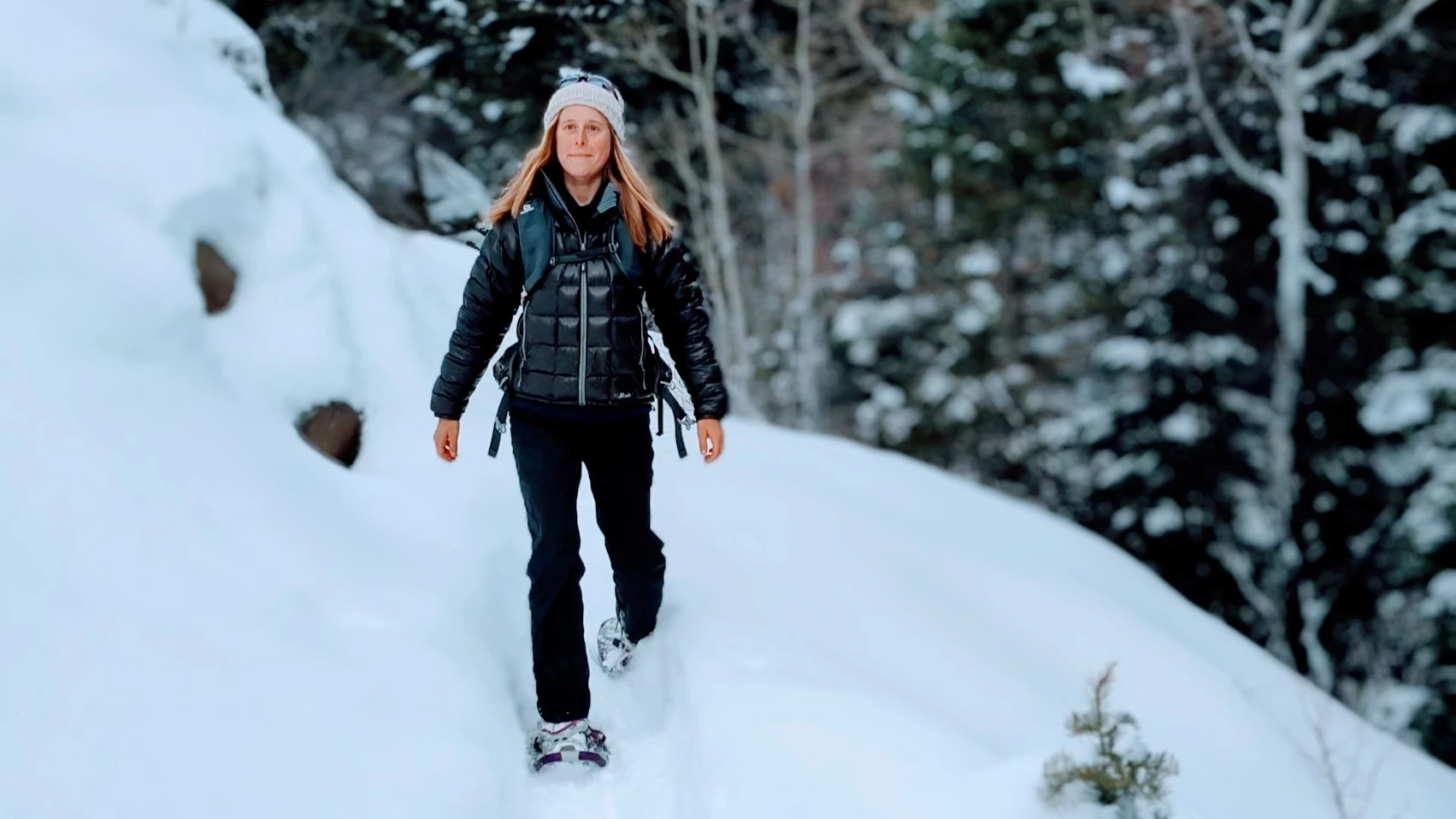 A woman snowshoeing with a natural, narrow gait on a snowy path.