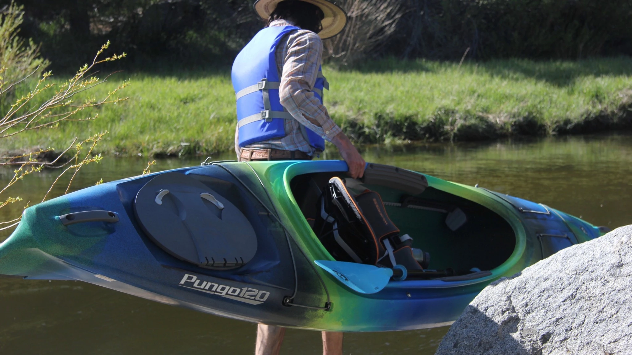 Two people carrying a kayak using the integrated bow and stern handles.