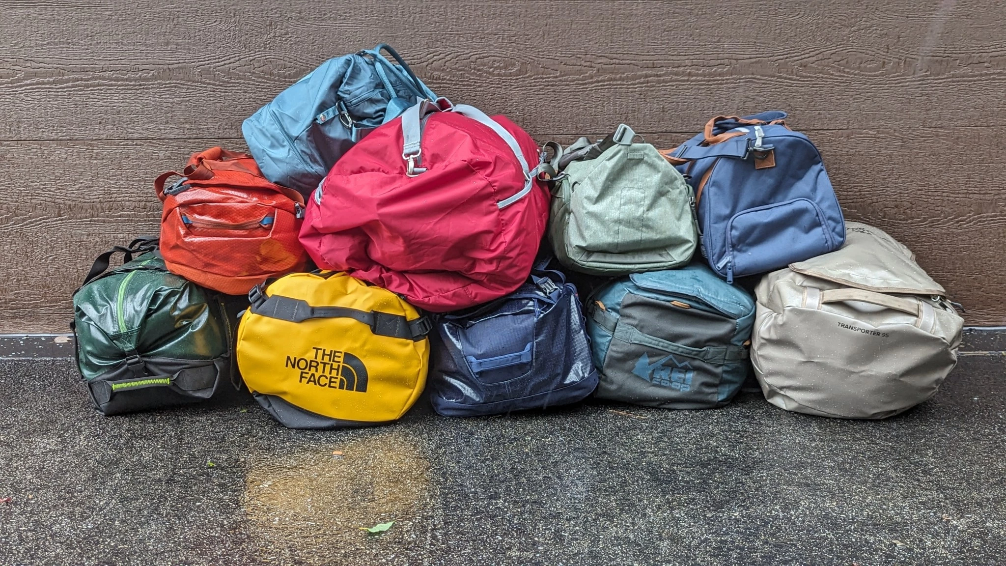 A group of tested duffel bags laid out in an outdoor field environment.