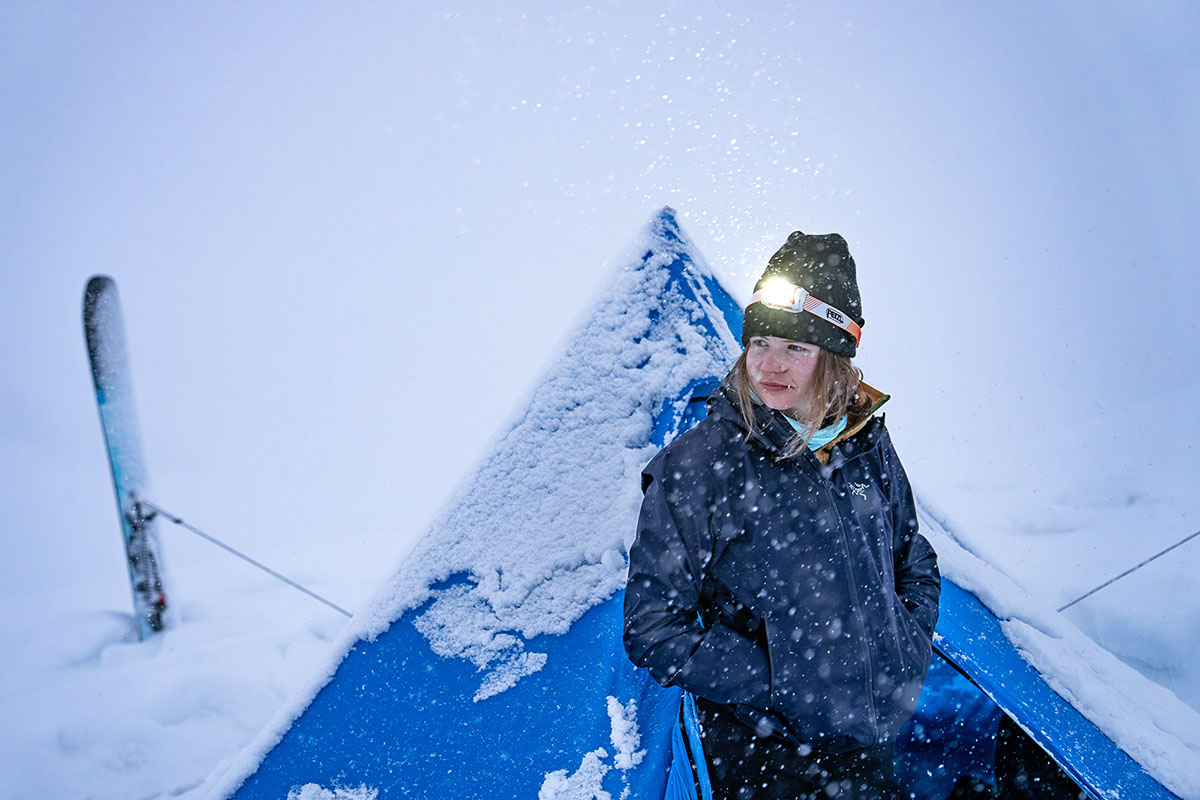 A woman huddled in a hardshell jacket during a snow storm on Mt. Rainier.
