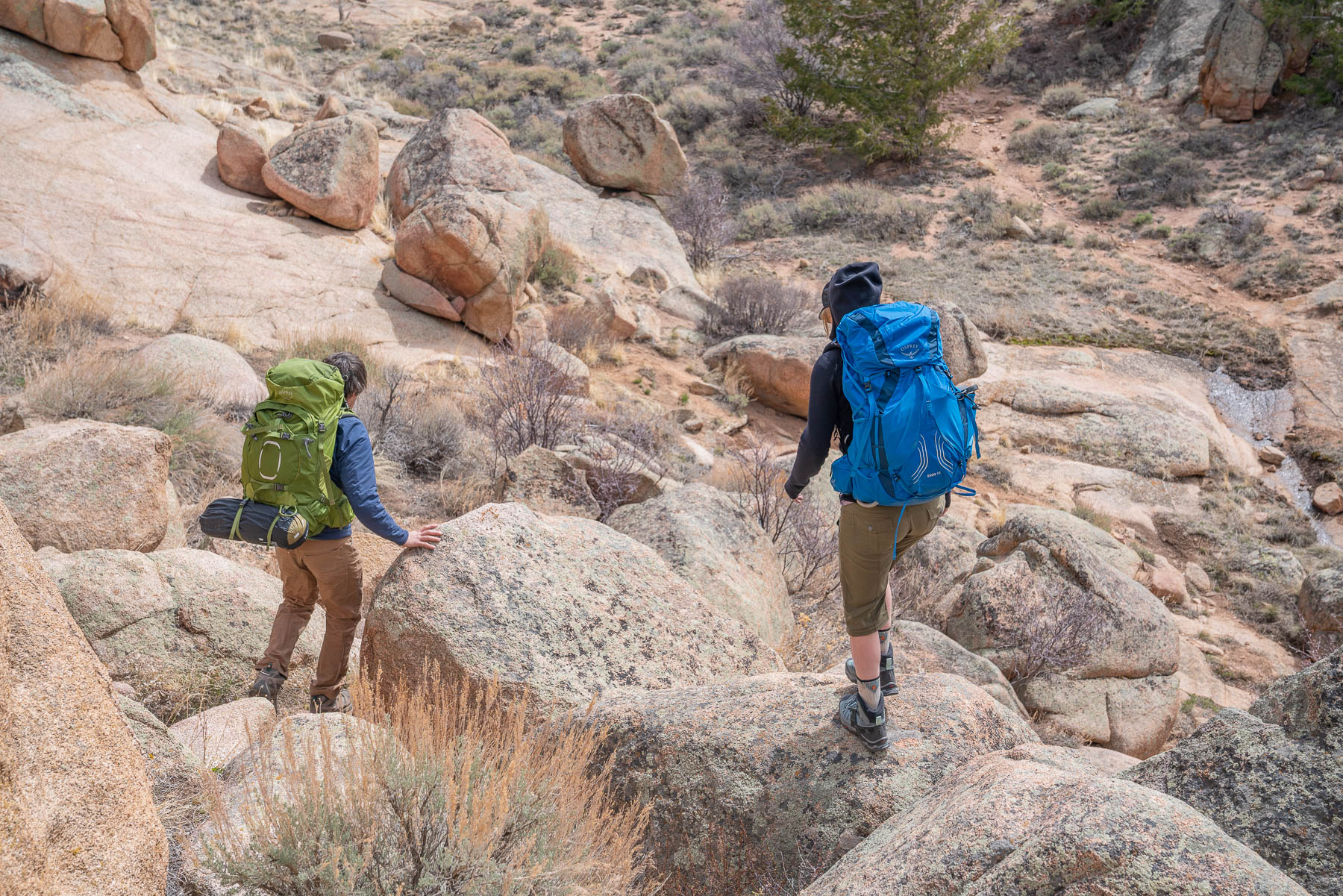 A pair of hiking boots providing stable footing on a steep, rocky mountain slope.