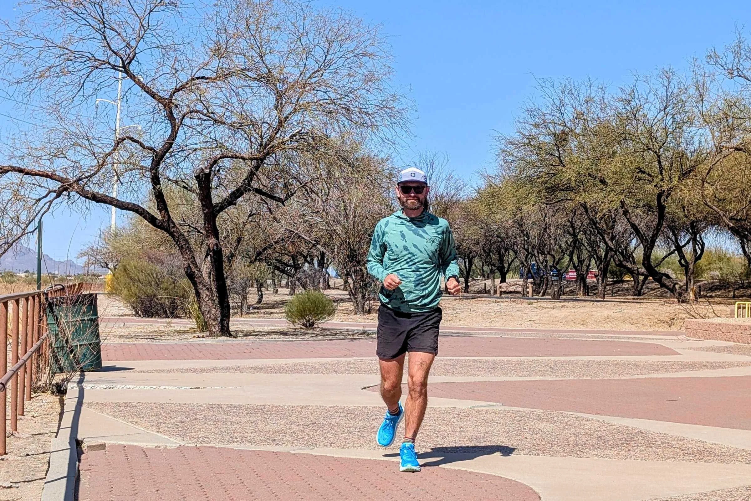 A runner wearing Hoka Clifton 10s during an ultramarathon training run on a desert road.