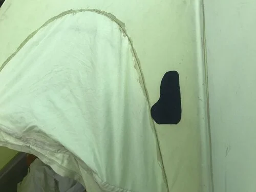 The same green tent fabric now successfully patched with a round-cornered transparent adhesive patch.