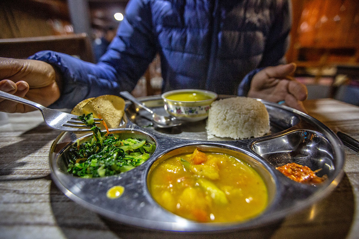 A traditional Nepalese meal of Dal Bhat served on a metal tray in a teahouse.
