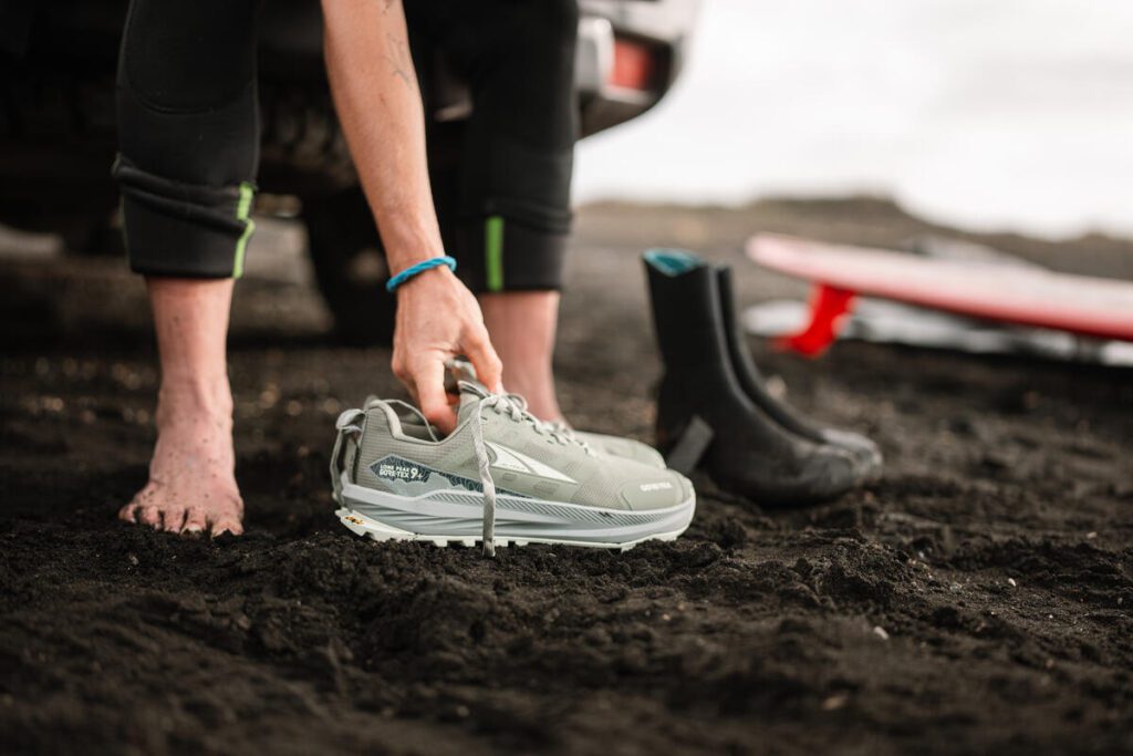 Female runner wearing Altra Lone Peak 9+ GTX on a muddy trail