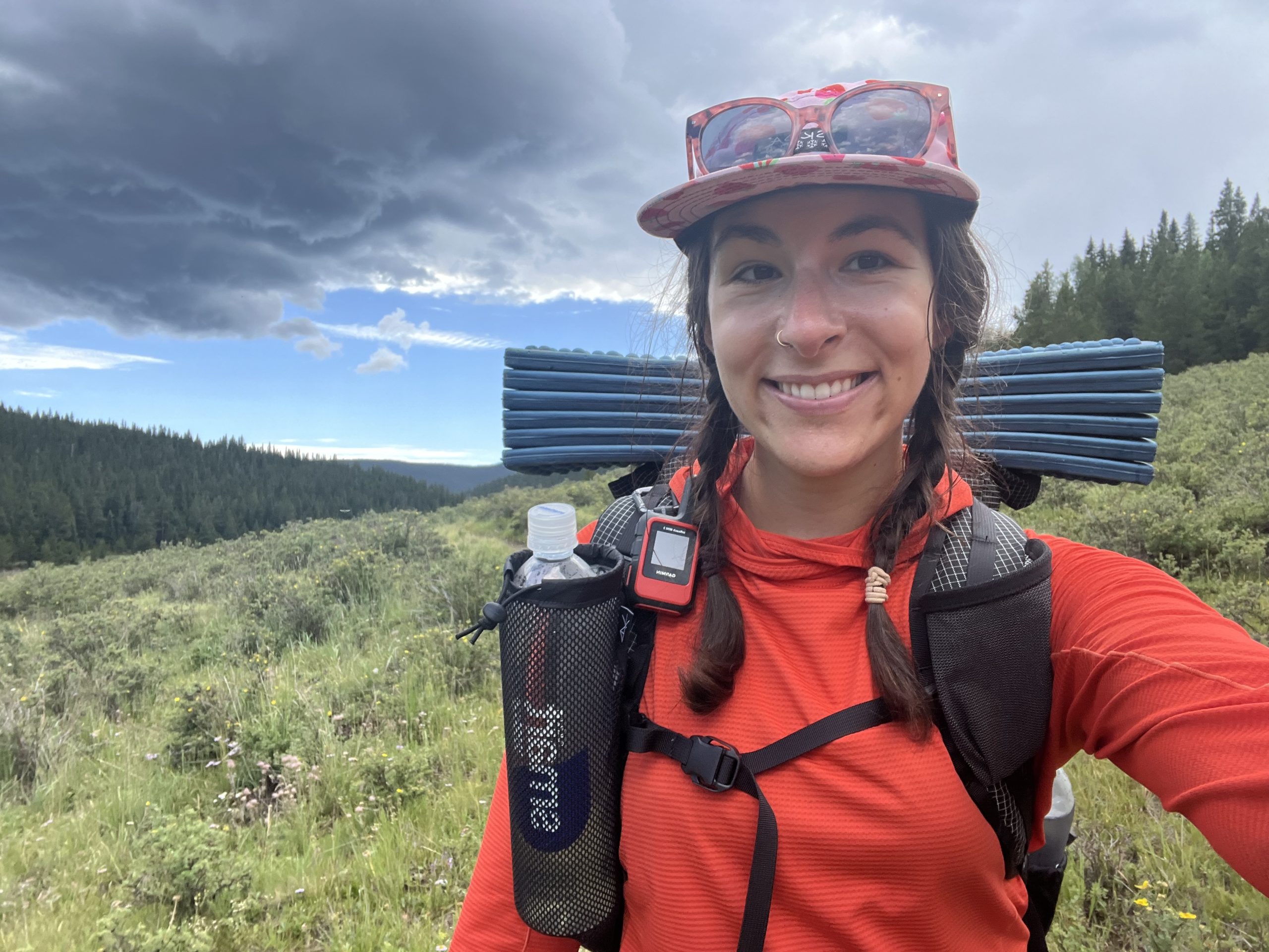 A hiker using the Garmin inReach Mini 2 while standing on a mountain trail.