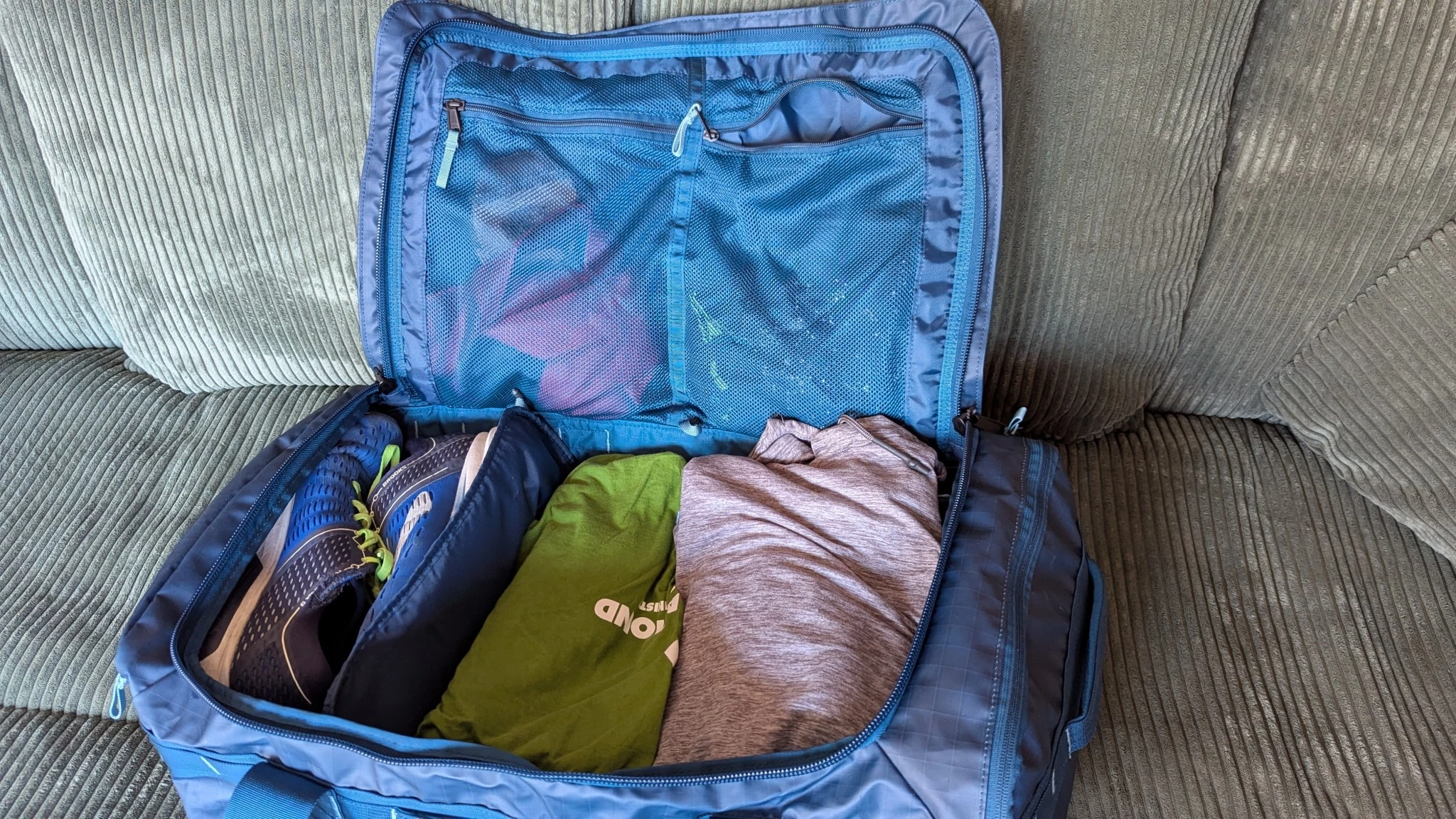 Interior view of a duffel bag showing mesh dividers separating shoes from clothes.