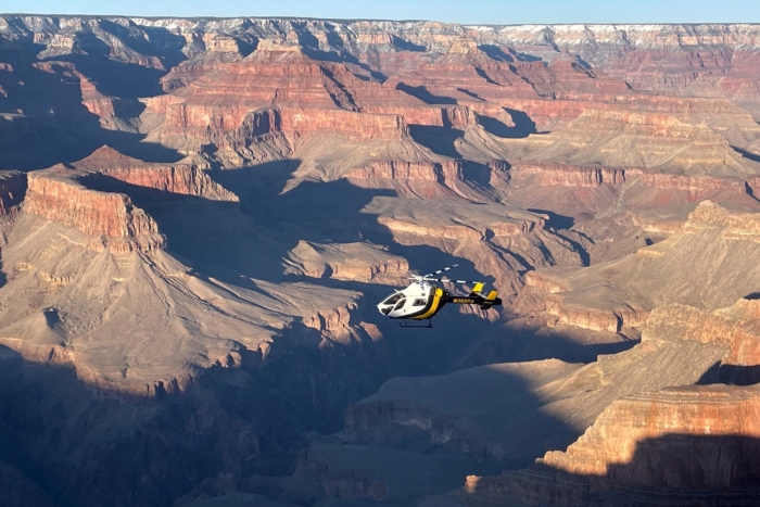 An NPS helicopter flying above the Grand Canyon rim during a safety mission.