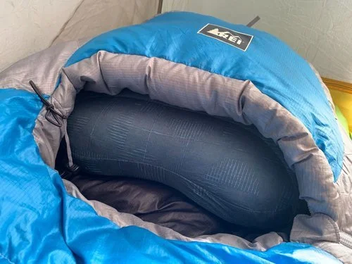 A Therm-a-Rest Air Head Down pillow tucked into the hood of a technical mummy sleeping bag.