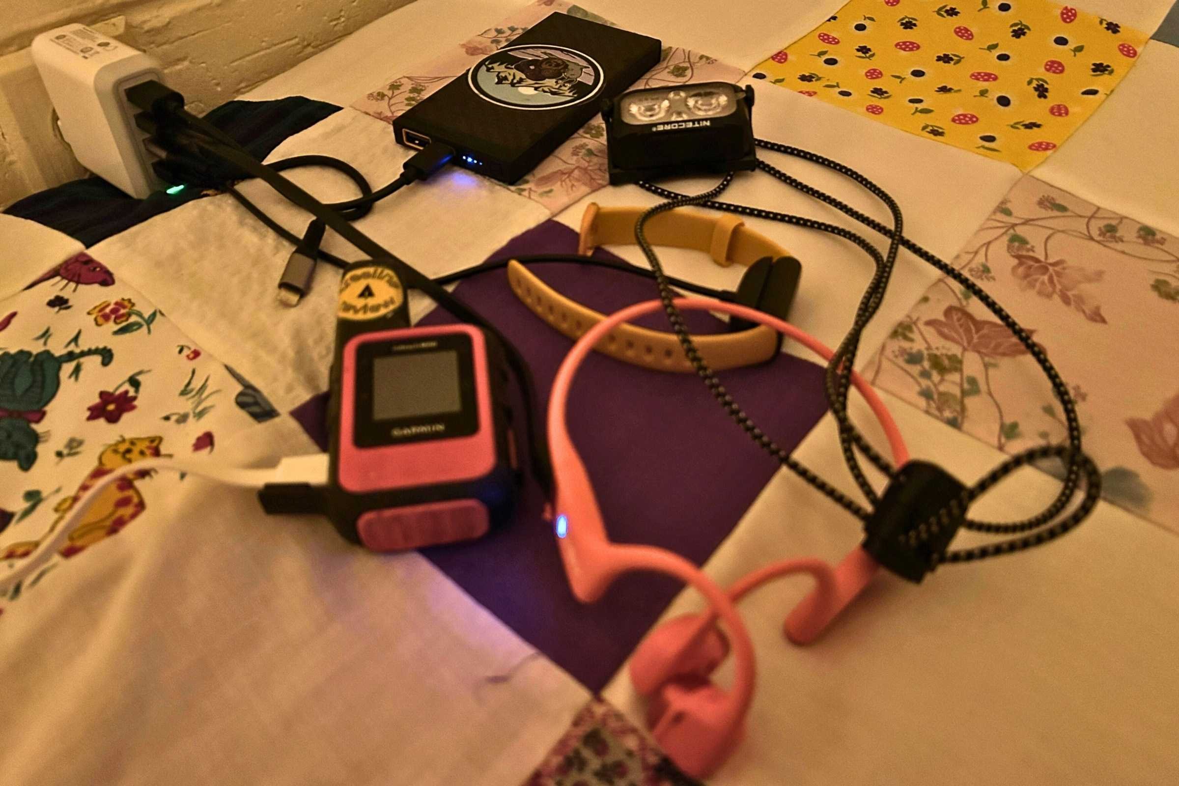 A 4-port USB wall charger with several devices and a power bank connected.