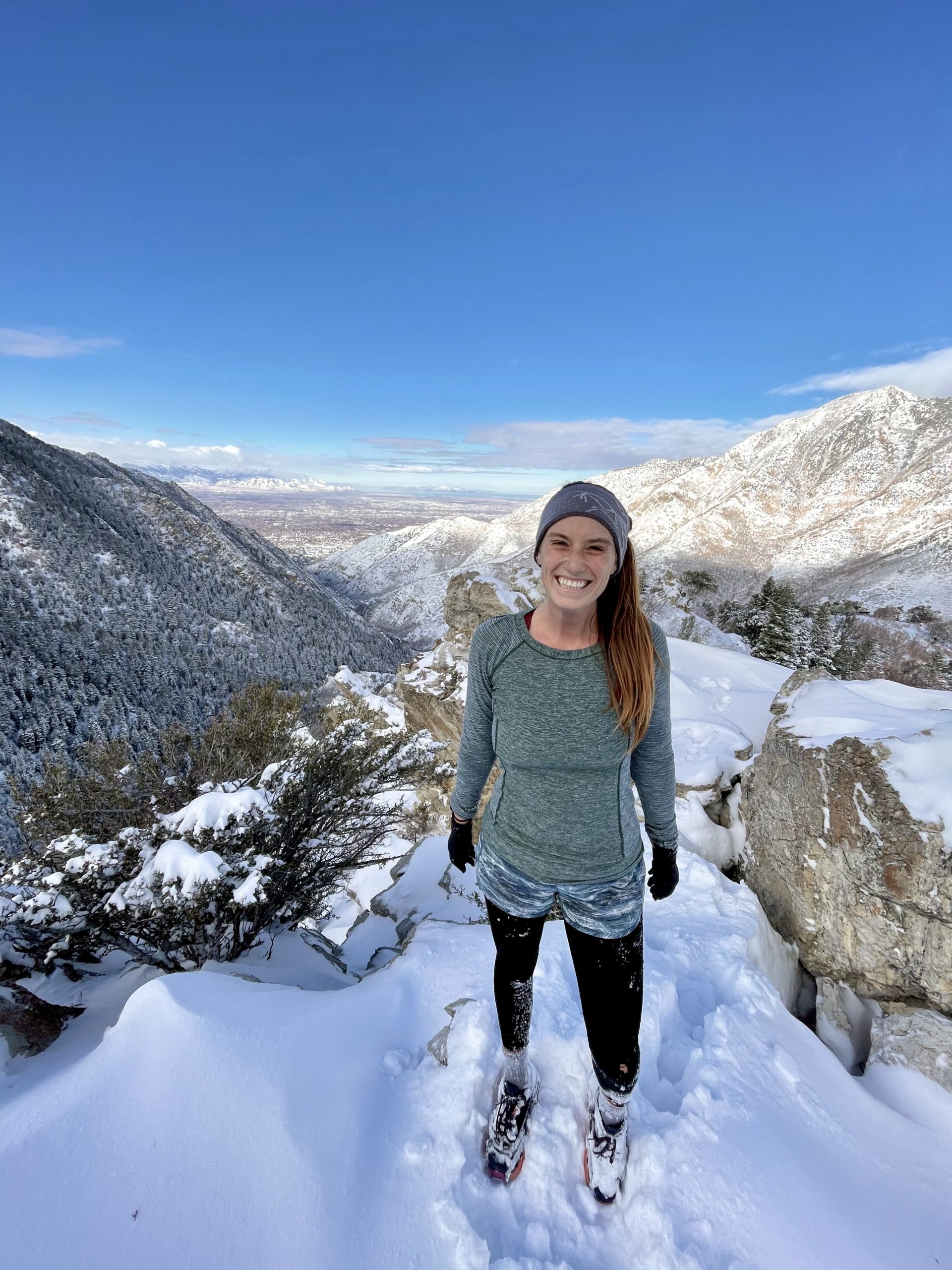 A woman running in winter gear, featuring merino wool leggings paired with a synthetic top.