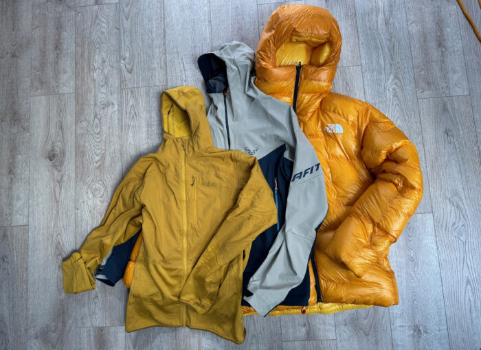 A person wearing a thick red down parka designed for extreme cold standing in deep snow.