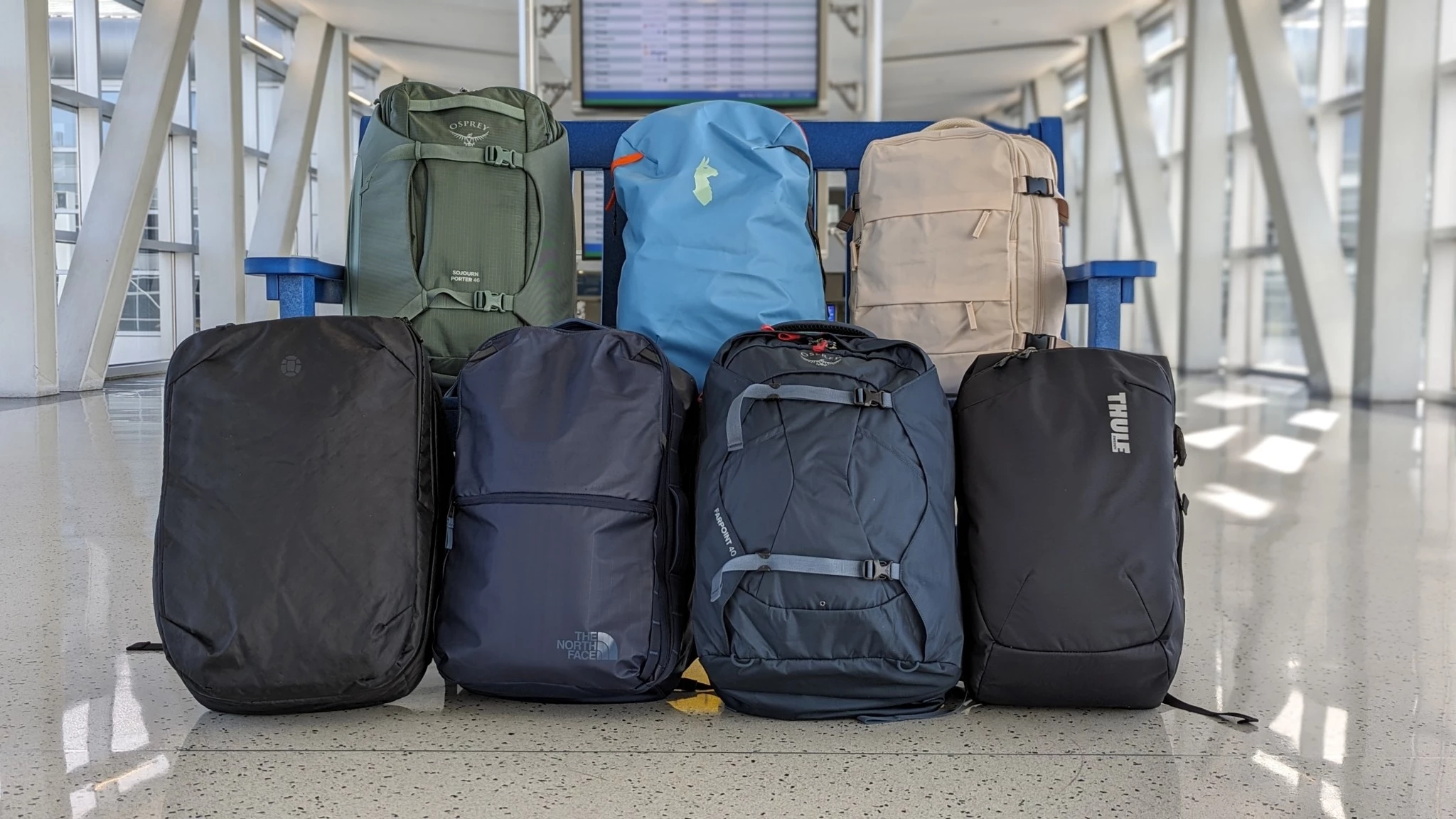 A collection of various modern travel backpacks lined up side-by-side.