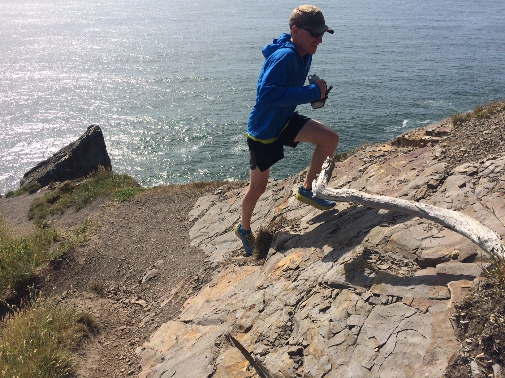 A runner wearing a breathable windbreaker jacket on a windy coastal trail.
