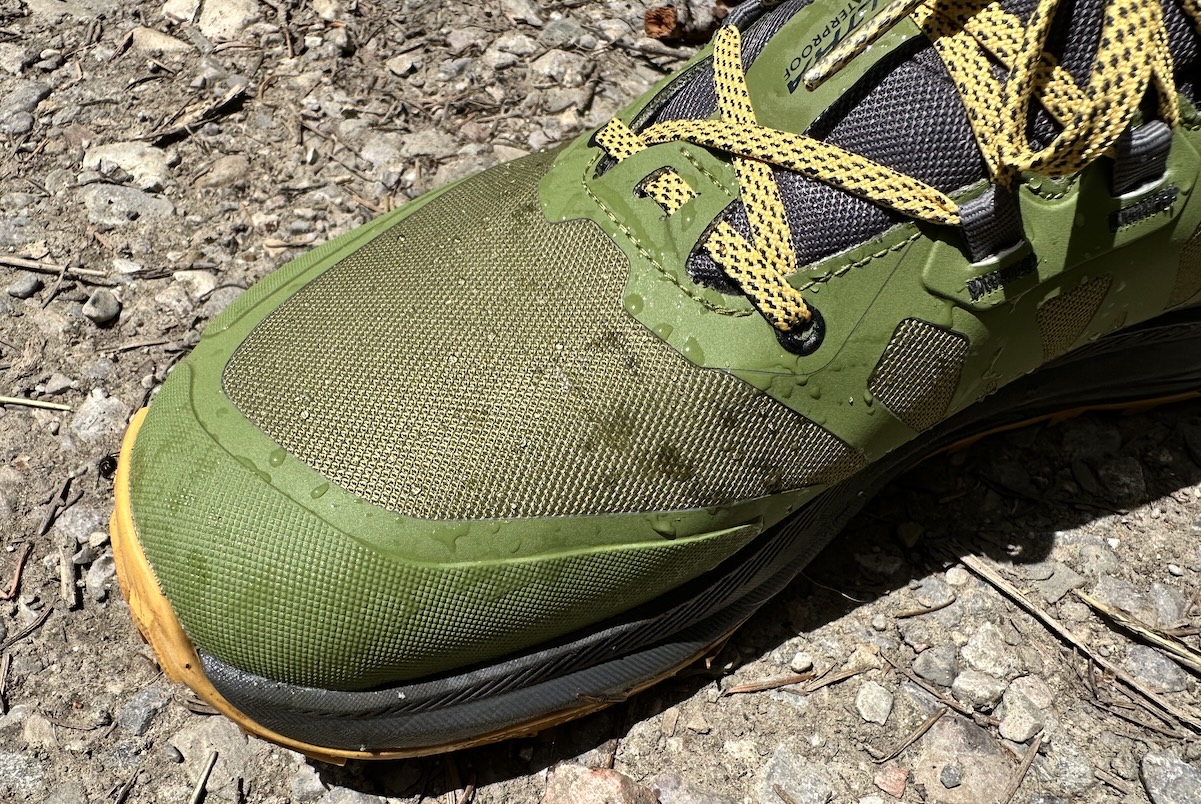 Close up of water droplets beading and rolling off the synthetic fabric of a hiking shoe.
