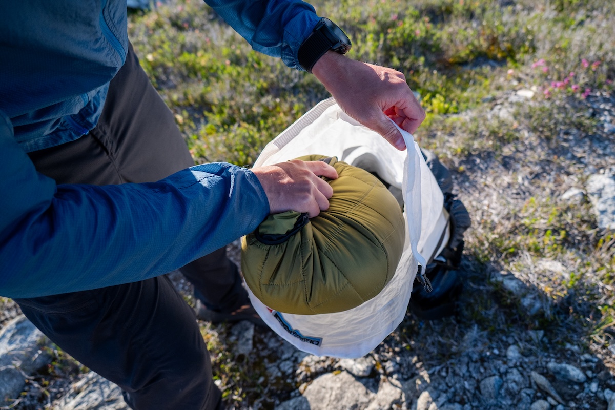 Hand stuffing a synthetic insulated jacket into a small integrated stuff sack.