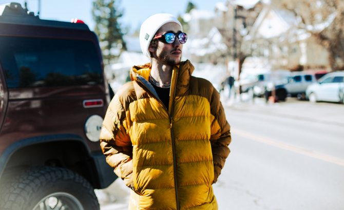 A person wearing a blue Rab Neutrino Pro puffer jacket outdoors in a cold, mountainous setting.