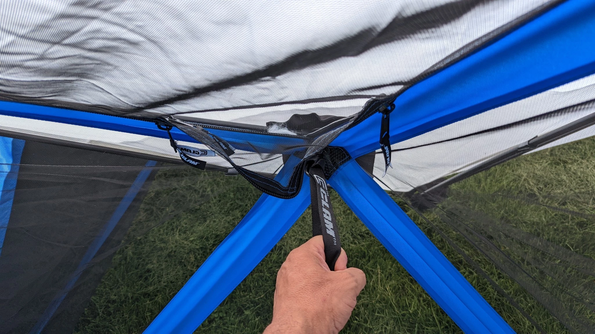 A person demonstrating the easy setup of a hub-style pop-up canopy by pulling a side handle.