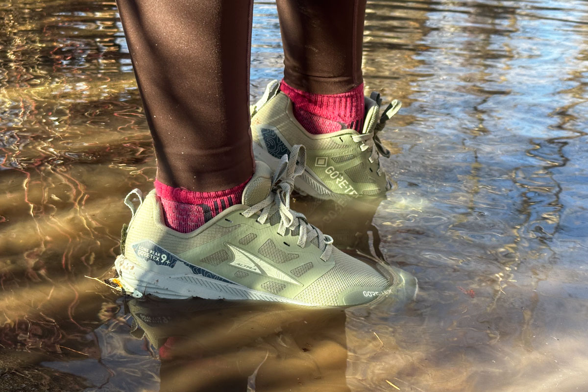 A pair of Altra Lone Peak shoes partially submerged in a pool of water.