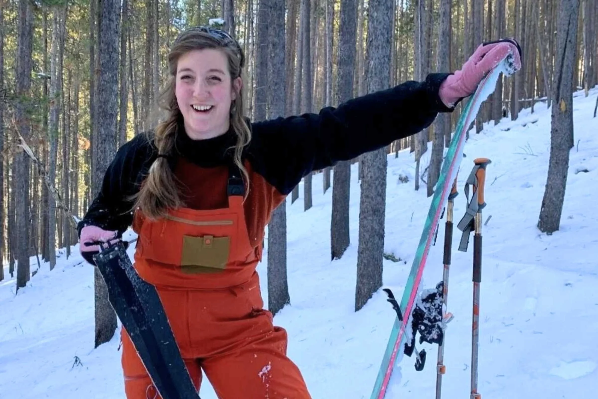 Hands in ski gloves handling climbing skins for backcountry touring.